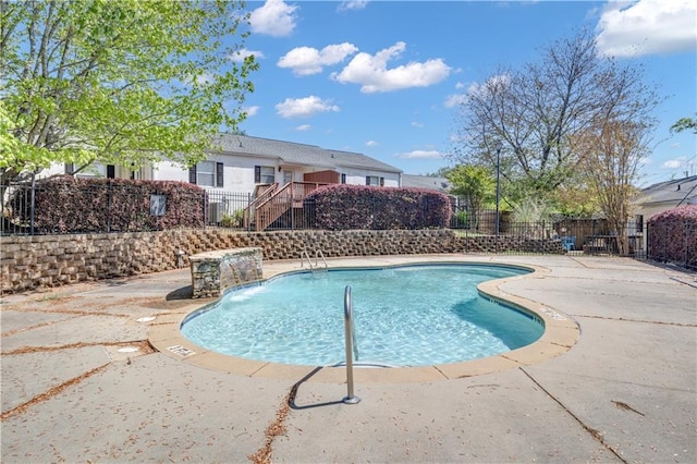 pool with a patio area, stairway, and fence