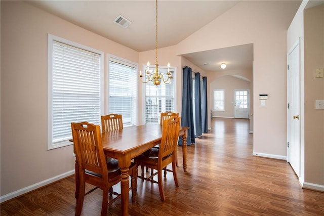 dining space featuring an inviting chandelier, vaulted ceiling, and hardwood / wood-style flooring