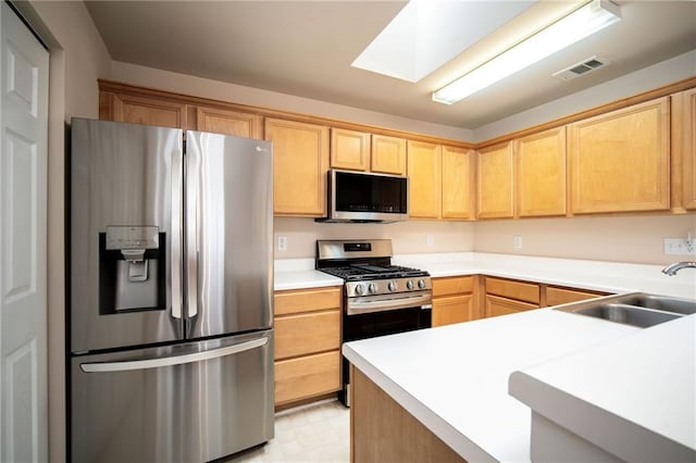 kitchen featuring light brown cabinets, sink, appliances with stainless steel finishes, and a skylight