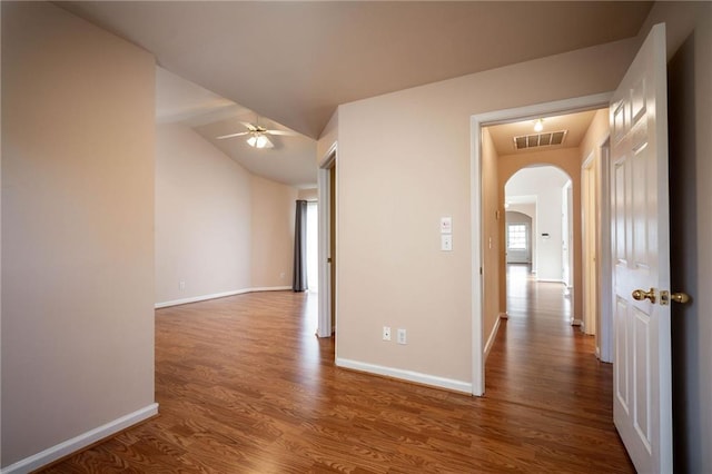 corridor with vaulted ceiling and hardwood / wood-style flooring