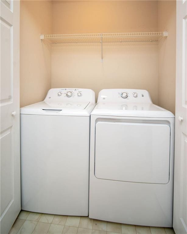 laundry area with separate washer and dryer and light tile patterned floors