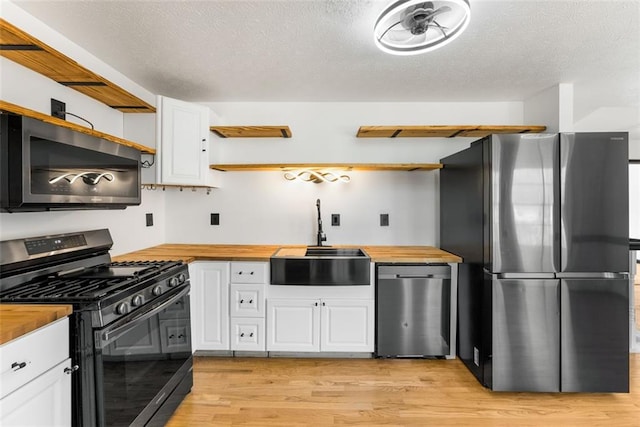 kitchen featuring appliances with stainless steel finishes, a sink, wood counters, and open shelves