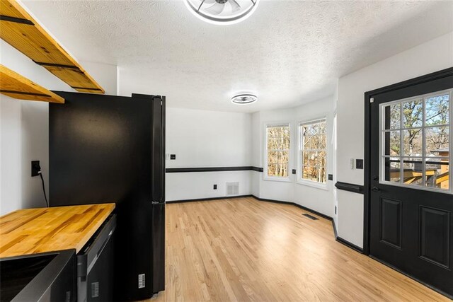 kitchen with visible vents, electric stove, freestanding refrigerator, a textured ceiling, and light wood-style floors