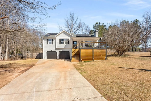 view of front facade featuring an attached garage, concrete driveway, stairway, roof mounted solar panels, and a chimney