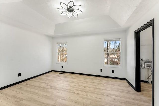 unfurnished bedroom with a raised ceiling, visible vents, and baseboards