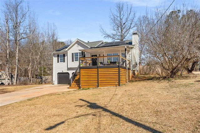 view of front facade with driveway, a garage, a chimney, stairs, and roof mounted solar panels