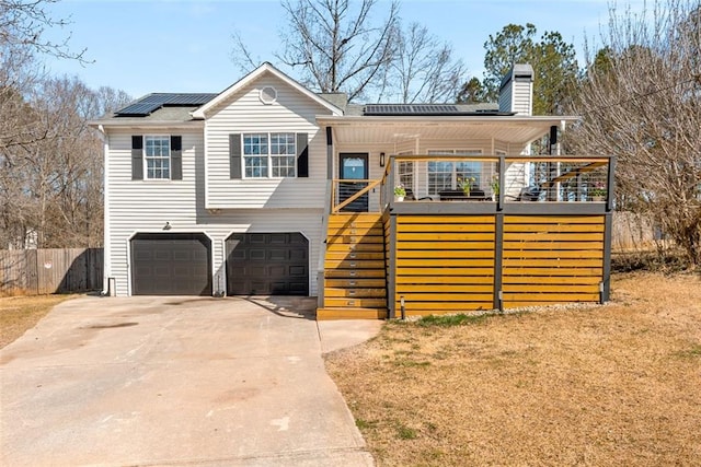 view of front of house featuring a garage, concrete driveway, stairway, roof mounted solar panels, and a chimney