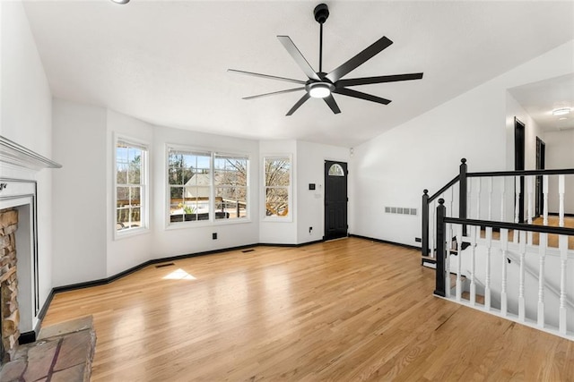 unfurnished living room featuring ceiling fan, light wood-type flooring, a fireplace, and baseboards