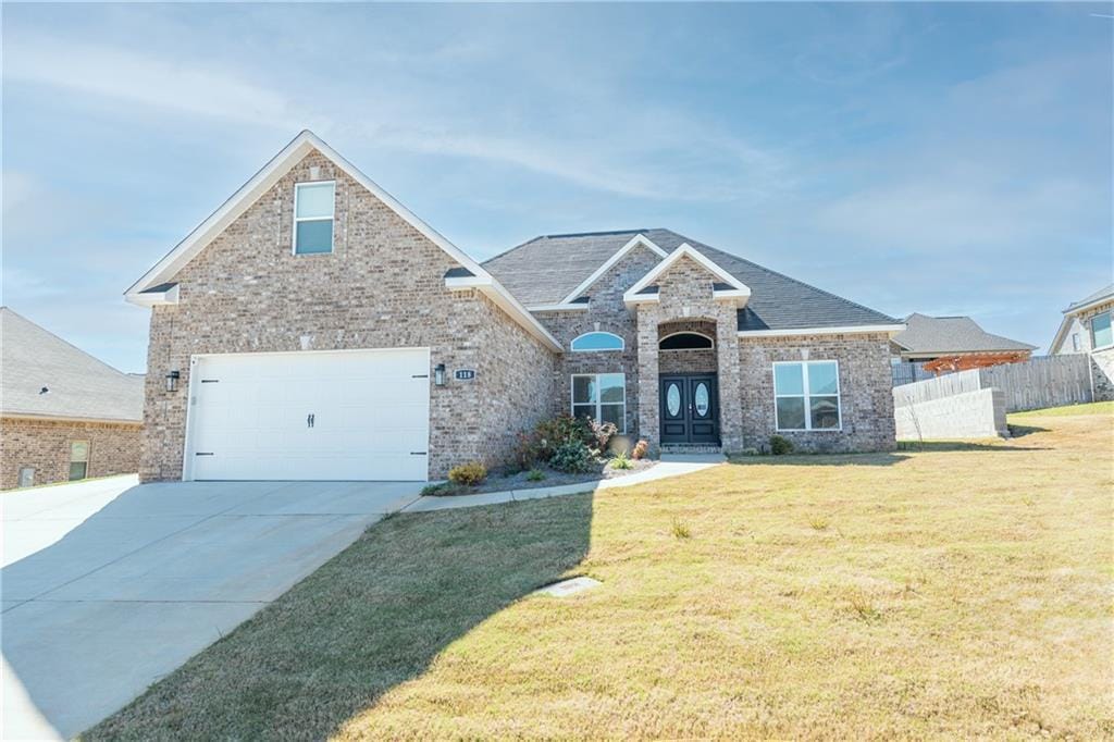 craftsman-style home featuring concrete driveway, brick siding, a front yard, and fence