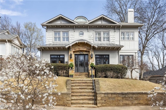 view of front facade featuring metal roof, brick siding, a chimney, and a standing seam roof