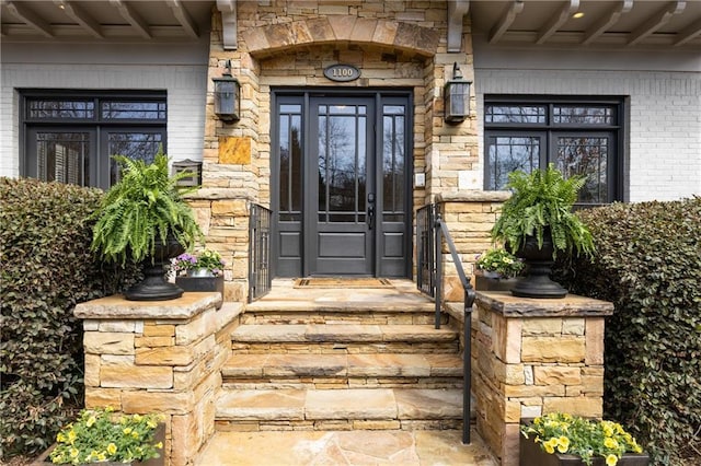 view of exterior entry featuring brick siding and stone siding