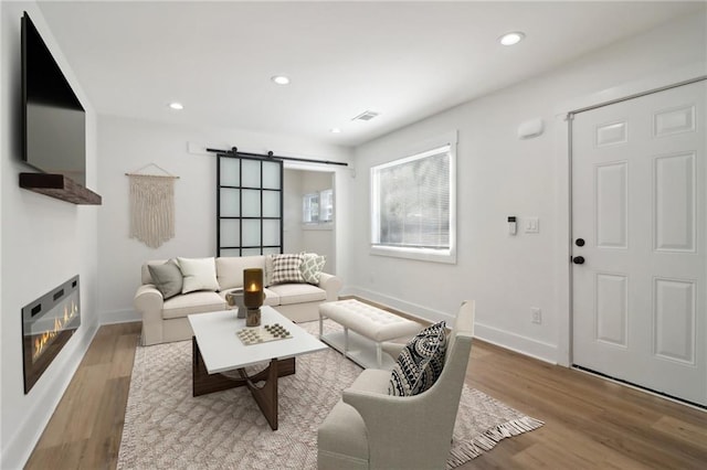 living room featuring a barn door and light hardwood / wood-style floors