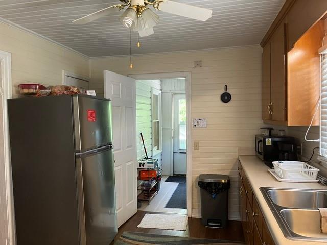 kitchen with dark hardwood / wood-style floors, sink, crown molding, appliances with stainless steel finishes, and ceiling fan