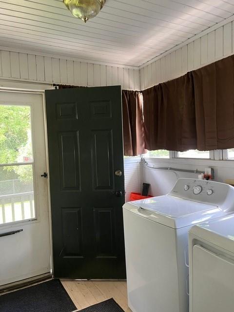 laundry area with washing machine and clothes dryer, light hardwood / wood-style floors, and wooden ceiling