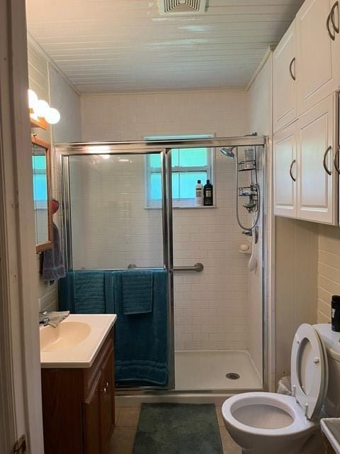 bathroom with vanity, toilet, and a shower with shower door