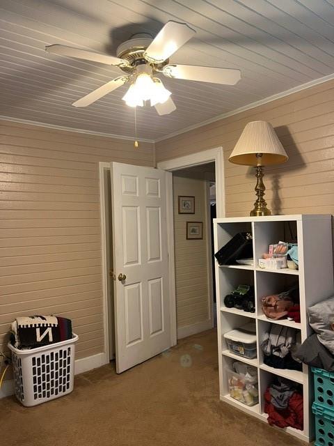 interior space featuring ceiling fan, ornamental molding, and carpet floors