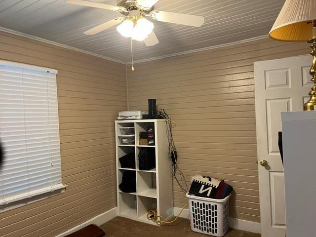 interior space featuring ceiling fan, crown molding, and wooden walls