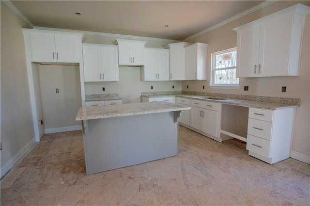 kitchen featuring white cabinetry, ornamental molding, light stone countertops, and a kitchen island