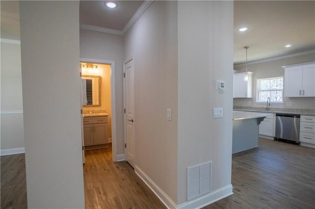 corridor featuring visible vents, wood finished floors, and ornamental molding