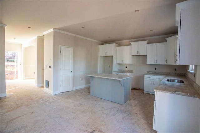 kitchen with sink, white cabinetry, crown molding, light stone counters, and a center island