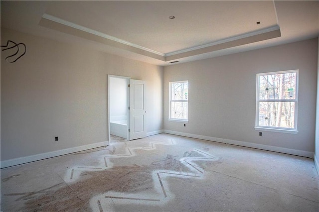 unfurnished room with crown molding, a tray ceiling, and baseboards