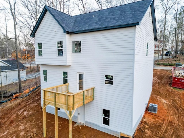 back of property with a shingled roof, a deck, and cooling unit