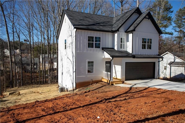 modern inspired farmhouse featuring board and batten siding, concrete driveway, central AC, and an attached garage