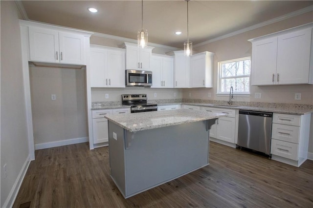 kitchen featuring white cabinets, a center island, stainless steel appliances, crown molding, and a sink