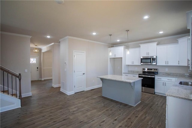 kitchen with appliances with stainless steel finishes, dark wood-style flooring, a kitchen island, and white cabinetry