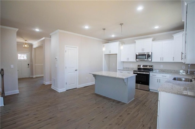 kitchen with dark wood-style floors, appliances with stainless steel finishes, white cabinetry, a sink, and a kitchen island