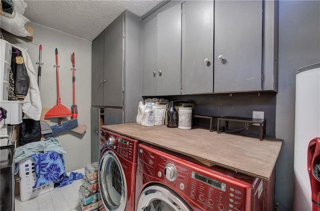 clothes washing area featuring tile patterned flooring, water heater, washer and dryer, cabinet space, and a textured ceiling