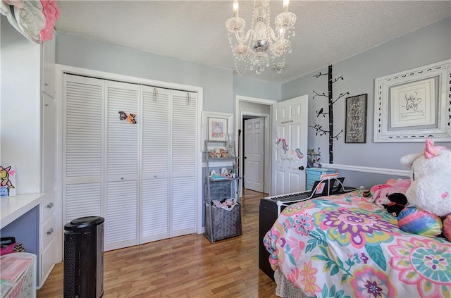 bedroom featuring light wood-type flooring, a textured ceiling, a closet, and an inviting chandelier