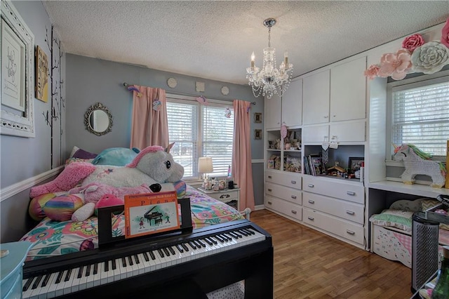 bedroom with a notable chandelier, a textured ceiling, and wood finished floors