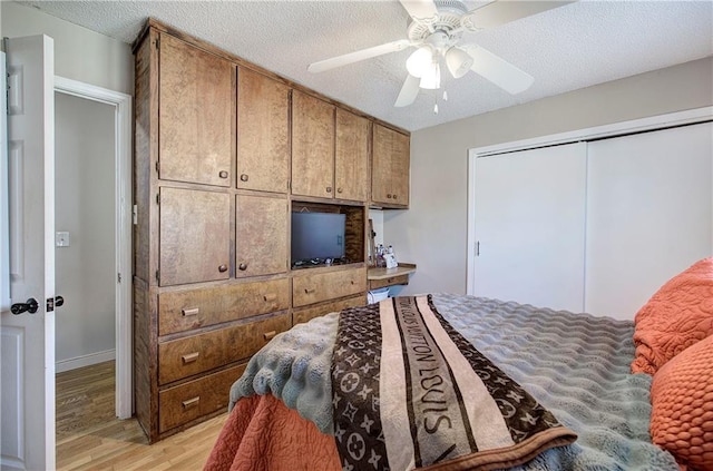 bedroom with light wood-style floors, a textured ceiling, a closet, and ceiling fan