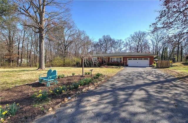 view of front of property featuring aphalt driveway, an attached garage, and a front yard