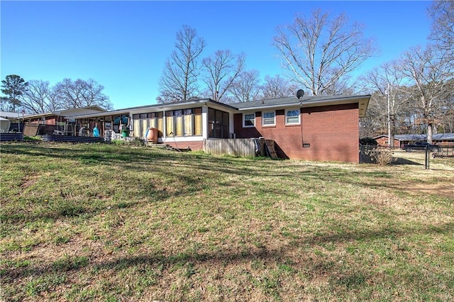 rear view of property with a lawn, fence, a sunroom, and crawl space