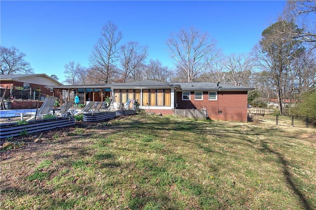 back of house with brick siding, a sunroom, a yard, and fence