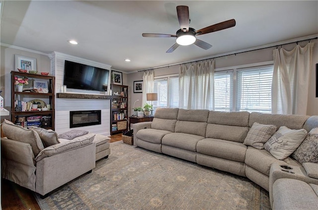 living area featuring a ceiling fan, wood finished floors, recessed lighting, a fireplace, and crown molding