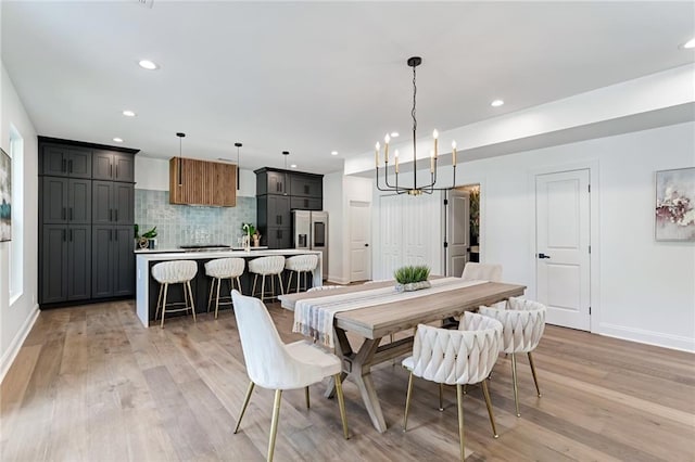 dining room with light wood-type flooring, sink, and a chandelier