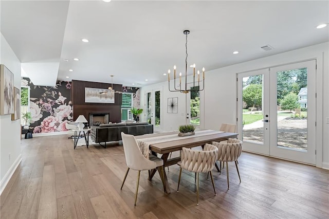 dining area with french doors, light hardwood / wood-style flooring, and a notable chandelier