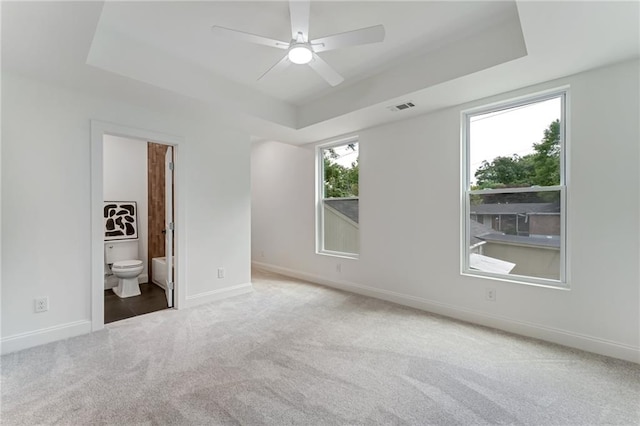 carpeted empty room with a tray ceiling and ceiling fan