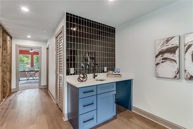 interior space featuring blue cabinetry, ceiling fan, sink, and light hardwood / wood-style flooring