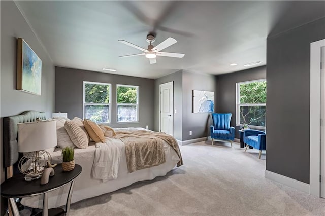 bedroom featuring light carpet, multiple windows, and ceiling fan