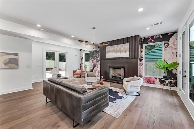 living room with a large fireplace, a wealth of natural light, hardwood / wood-style floors, and french doors