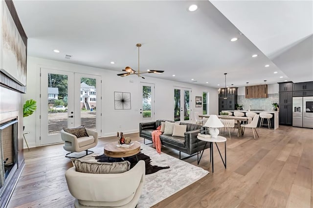 living room with a notable chandelier, light hardwood / wood-style floors, and french doors