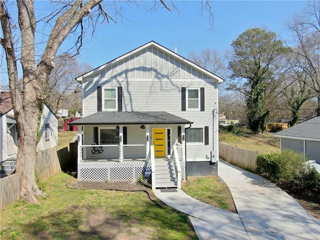 view of front of home featuring board and batten siding, a porch, a front yard, and fence