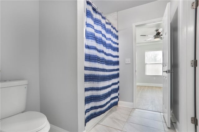 bathroom with curtained shower, toilet, and baseboards