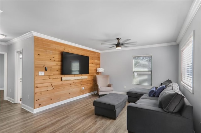 living room with wood finished floors, plenty of natural light, ornamental molding, and a ceiling fan