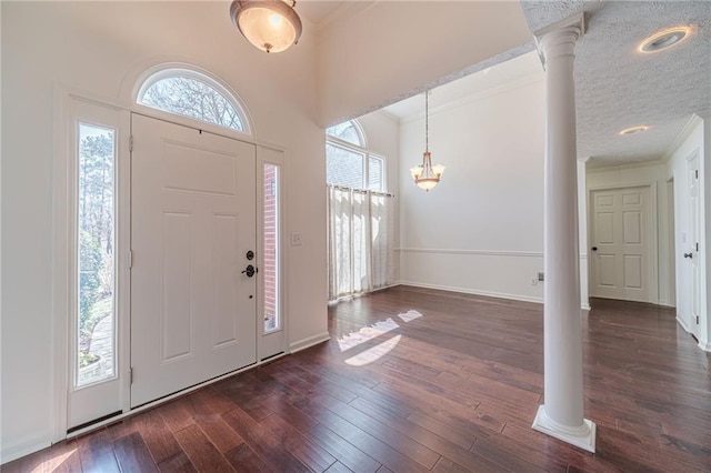 foyer featuring crown molding, decorative columns, dark wood-style floors, and a healthy amount of sunlight