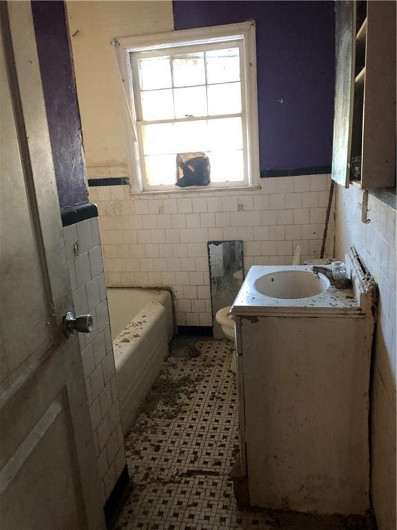 bathroom with a washtub, toilet, vanity, and tile walls